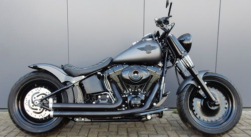 Seitenansicht eines schnittigen schwarzen Motorrads im Low-Rider-Design mit auffälligem Motor und minimalistischem Styling vor grauem Hintergrund.